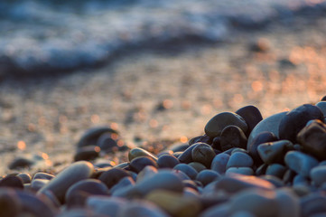 pebble stones on the sea beach, the rolling waves of the sea with foam