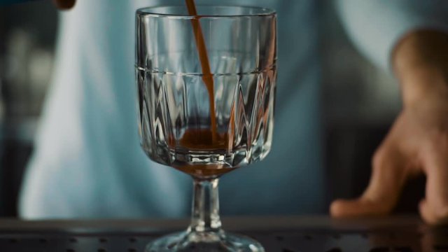 Slowmotion shot of a bartender in bar pours a juice into a glasses