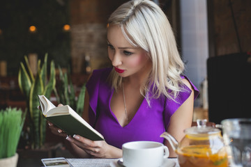 Obraz na płótnie Canvas Cute Woman Reading Book in Restaurant