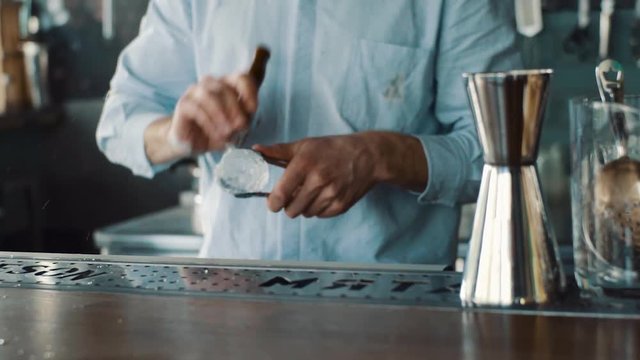 Bartender carves ice using ice pick