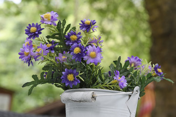 tischschmuck aus kunstblumen im blechkübel in einem gartenlokal