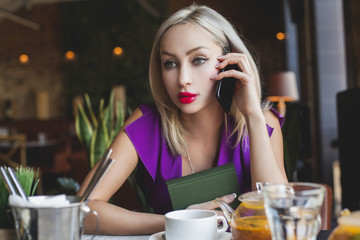 Cute woman chatting with smartphone in cafe