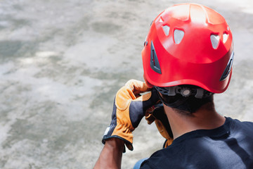 Work safety background concept.Soft focus close up young man Asian wear the red helmet with leather glove for job high critical hazard area industry.Free space for creative design text and content.