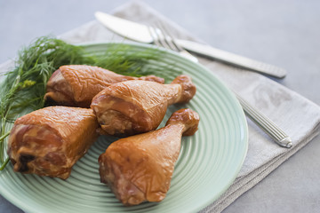 Smoked chicken drumsticks on a green plate.