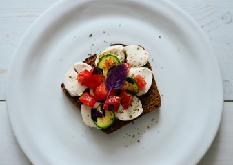 Delicious homemade toast with dark bread, mozzarella cheese and vegetables top view 