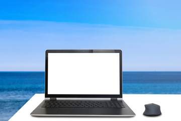 Laptop on a white desk in front of crystal blue sea - Enjoying summer concept