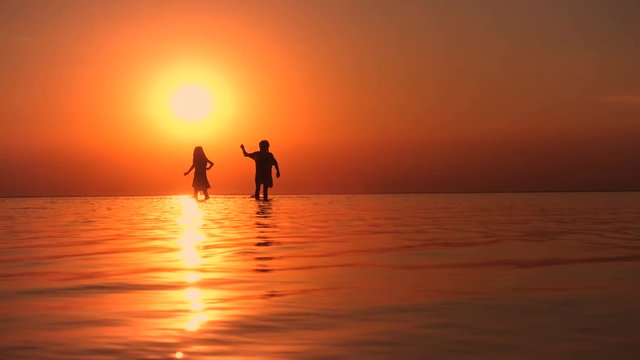 children walking by the sea at the sunset time
