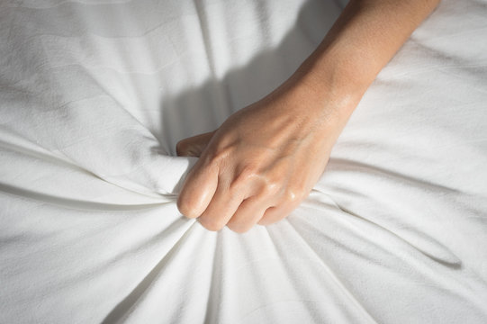 Female hand having sex on a bed.