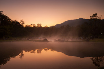 Fototapeta na wymiar A natural fountain of clear water in morning time with cloudy foggy located in front of mountain at north of Thailand. Concept of healthy place 