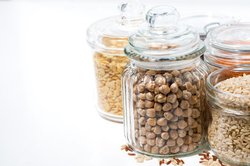 assortment of cereals and legumes in glass jars on white background, closeup