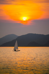 Fototapeta na wymiar Reflection of running boat on the sea under sunset with colorful of sky located at east of Thailand