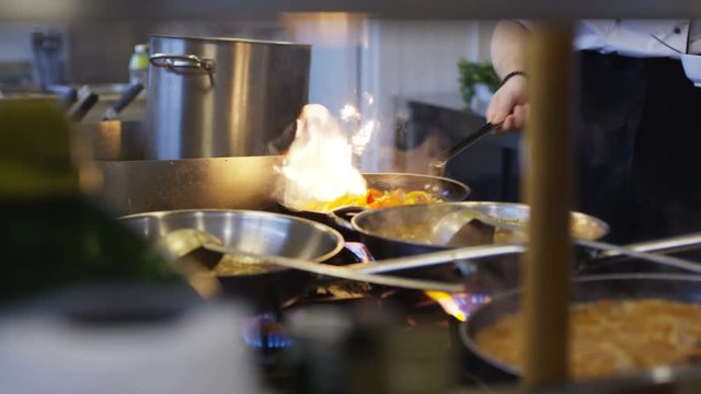 Cooking in wok pan with hard fire burning in slow motion
