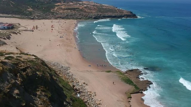 Aerial view of a cliff in the portuguese coastline. Sand beach aerial, top view of a beautiful sandy beach aerial shot with the blue waves rolling into the shore