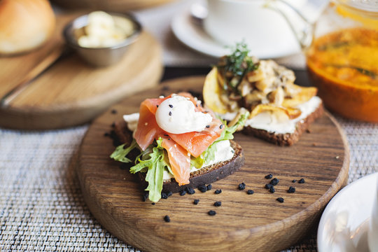 Danish smorrebrod sandwich with salmon fish and egg on wooden board. Restaurant food