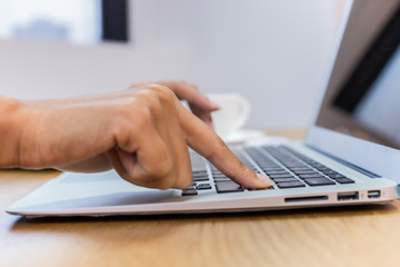 Business people are hand typing on silver color laptop computer put on table