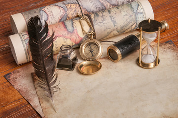 Quill pen on old paper sheets with old rolled maps and vintage items
