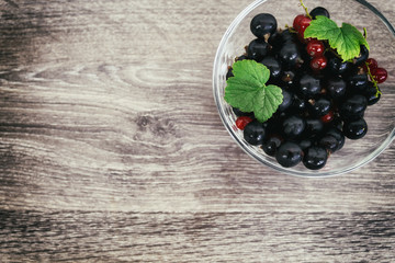 red and black currant in a bowl on a wooden old background. Vintage