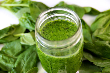 Green smoothie in jar, overhead on glass, healthy drink with vegetable leaves, background