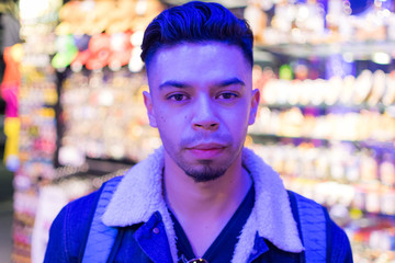 Chico joven con mirada fija con luces azules y fondo naranja