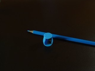 A blue pencil and a sharpener on a dark.