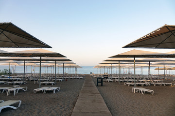 Fototapeta na wymiar Sun loungers with umbrella on the beach. Tourism industry.
