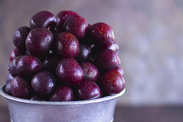 Ripe cherry in a metal bucket on a dark background.
