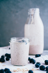 Smoothies for the summer detox made with banana, blueberries, oranges and oat classic, over a white towel against a gray background