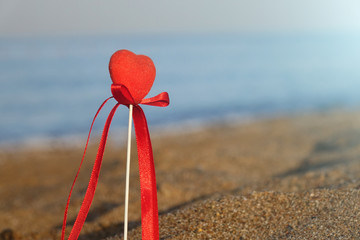 Valentine's day greeting card concept, red heart on pristine sandy beach, honeymoon vacation background.