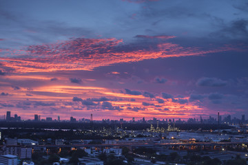 A night landscape view of city and Oil refinery industry under colorful sky at sunset time