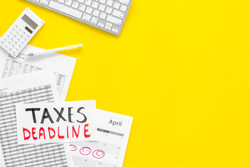 Fototapeta premium Taxes deadline words on office work desk with calendar and bills on yellow background top view copy space. Circled dates