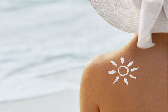 Woman With Suntan Lotion At The Beach In Form Of The Sun. Portrait Of Female With the Drawn Sun On a Shoulder On The Pool