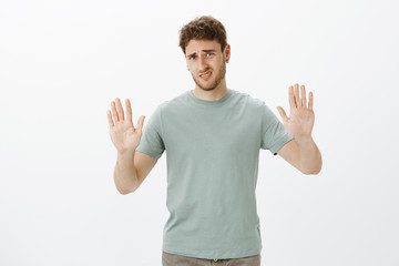 Enough, do not bother me. Displeased and disgusted charming man in t-shirt, pulling hands towards...