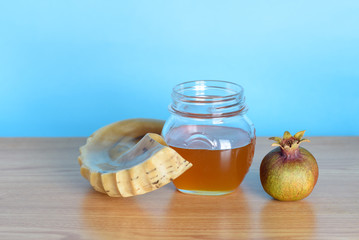 Rosh Ha Shana - Jewish new year composition of pomegranate,  jar of honey and Shofar horn for Rosh Hashanah on wooden table over blue background.Greeting card with copy space.