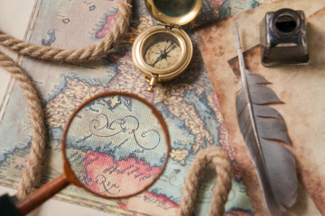 Planning a trip: closeup view of a magnifying glass on an old map with vintage items