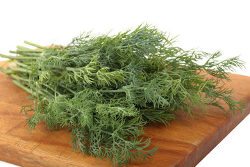Bunch of the fresh dill leaves on a wooden cutting board isolated on a white