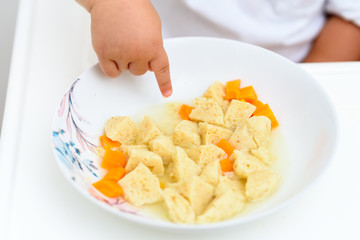 Soup in plate for Child, cute hand.Traditional matzoh ball (kneidlach) soup.White  bowl with authentic matzo ball chicken taste hot soup ( bouillon ) tradition Jewish food for Passover and every day.