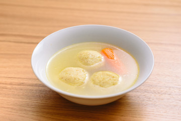 Traditional matzoh ball (kneidlach) soup.White  bowl with authentic matzo ball chicken taste hot soup ( bouillon ) tradition Jewish food for Passover and every day.