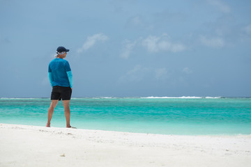 A man stands on the beach and looks out to sea