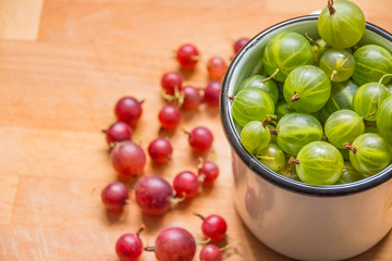 gooseberries in a cup. Gooseberries fresh berries. red green gooseberry on wooden background.Different homemade summer berries. Selective focus. Copy space