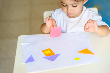 Cute little girl make applique  glues colorful house, applying color paper using glue while doing...