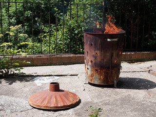 Fototapeta premium Destruction of garbage by means of burning in a Garden incinerator bin. Cause smoke, which air pollution. Not helping the environment.