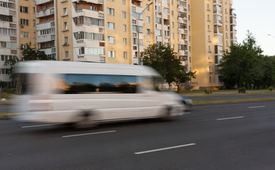 Movement of a blurred white minibus along the highway during the day