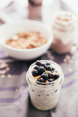 Vanilla chia parfait on a glass mason jarr topped with blueberres, shallow depth of field, selective focus technique.