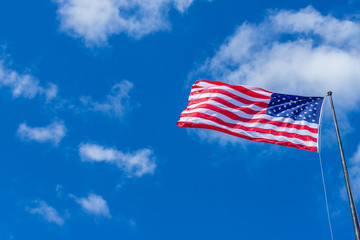American USA Flag waving with cloudy blue sky on a sunny day