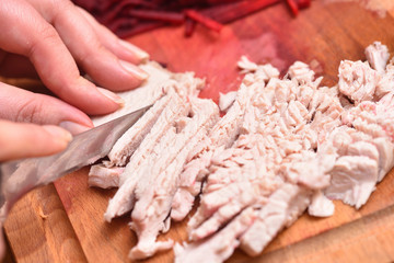 Sliced boiled turkey meat. Female hands with a knife cut boiled turkey meat