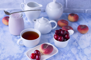 White cup of tea with thin waffles, yogurt and fresh cherry.