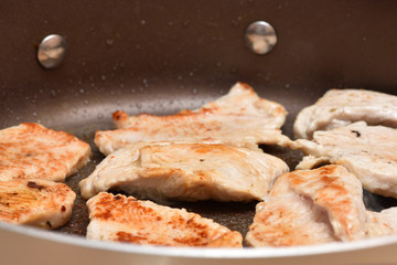 Beautiful turkey meat is fried in a round frying pan. Close-up