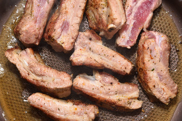 Beautiful and ruddy pork ribs are fried in a frying pan. Close-up