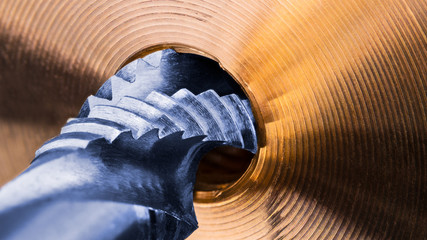 Spiral flute tap and detail of golden metal part. Artistic close-up of the silver-blue steel...