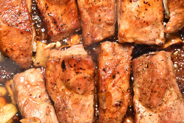 Beautiful and ruddy pork ribs are fried in a frying pan. Close-up